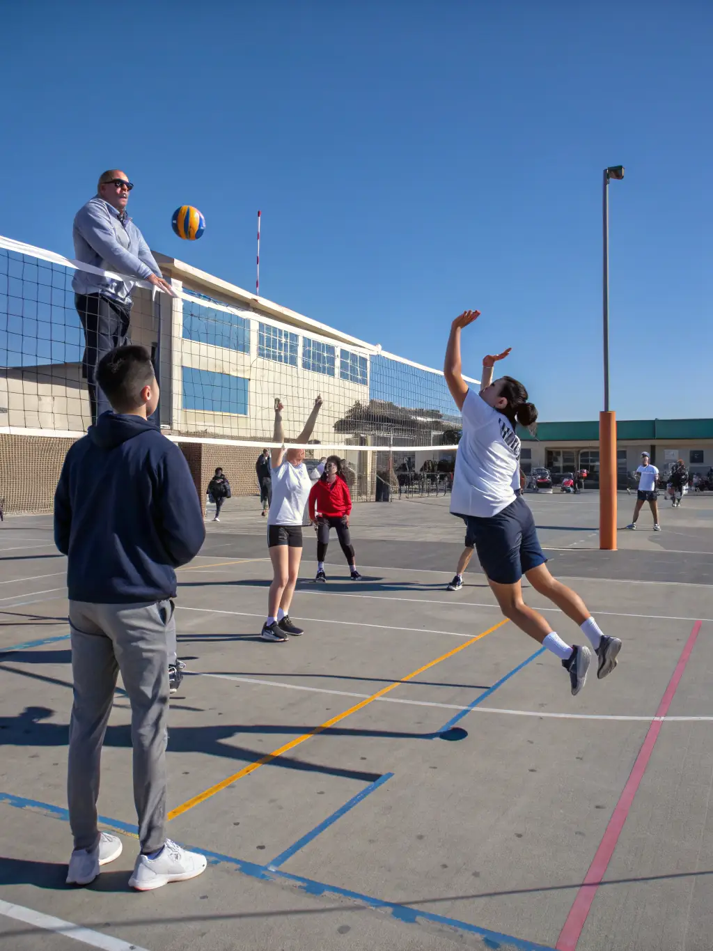 Students engaged in a volleyball match, demonstrating communication and collaborative play.